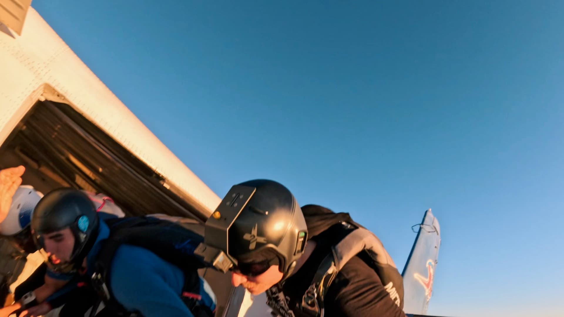 Skydivers exiting the plane at sunset