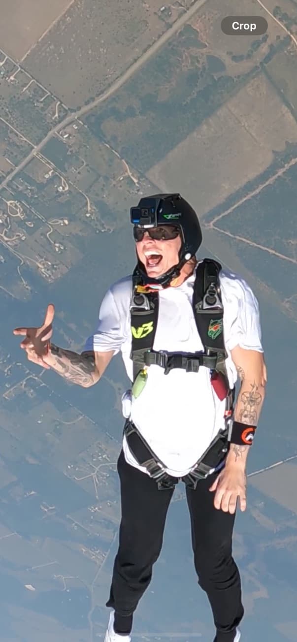 Skydiver stoked in freefall with ground below